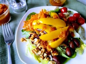 Salad of greens, yellow pepper, olives, carrots, tomatoes, walnuts with pumpkin vinaigrette salad dressing