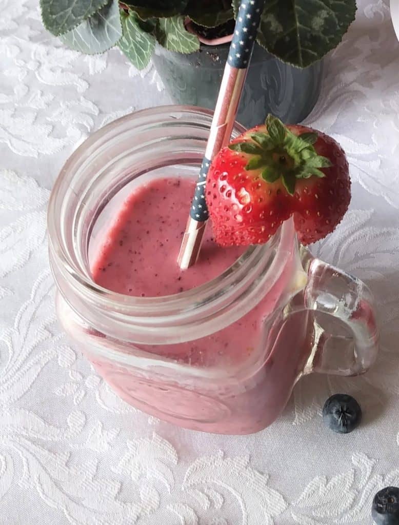 vegan berry smoothie in glass mug with strawberry garnish