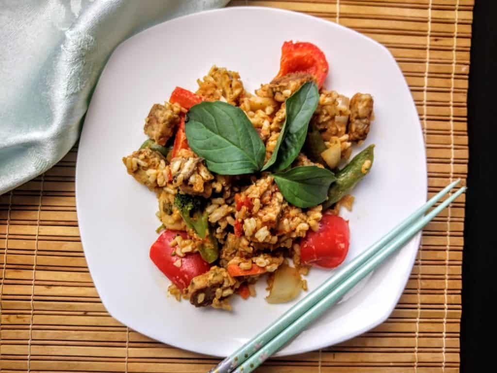 Thai peanut tempeh with rice on white plate with chopsticks