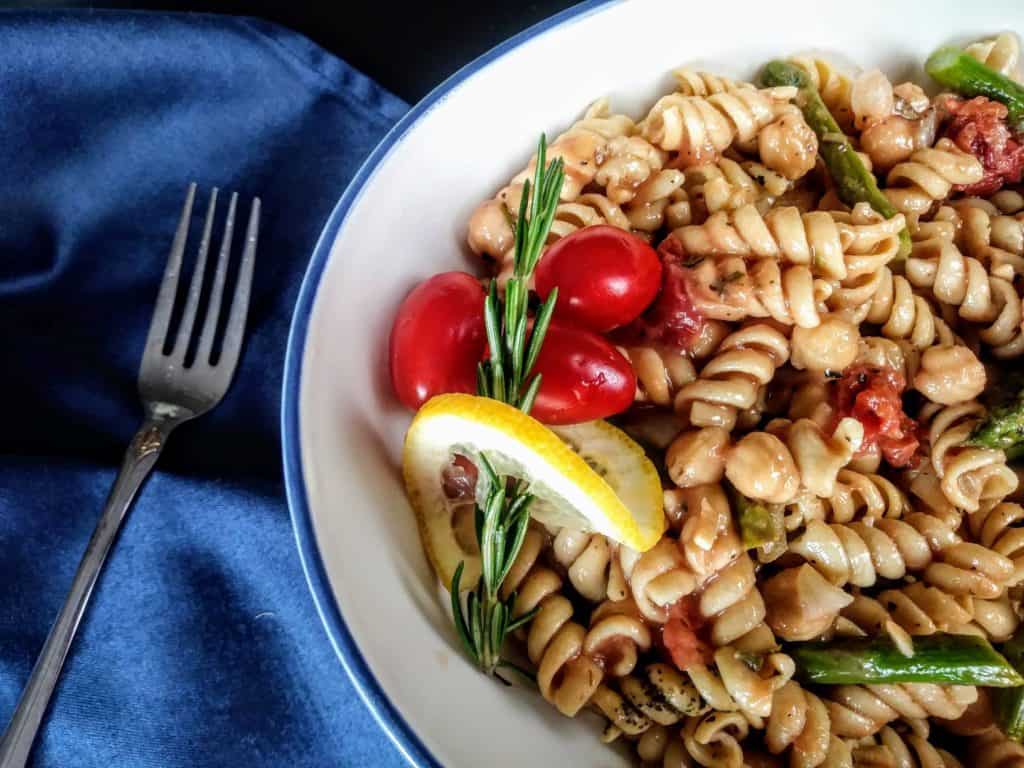 One pan pasta with chickpeas and tomatoes with blue napkin and fork
