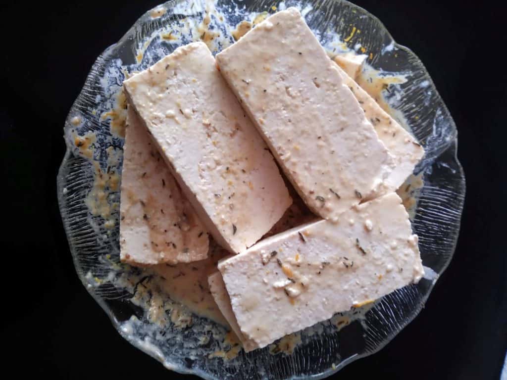 marinating orange tahini tofu on glass plate