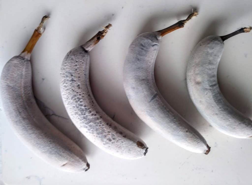 4 bananas defrosting on white cutting board