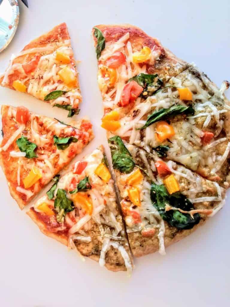 Cheesy Vegan Pizza sliced on white cutting board