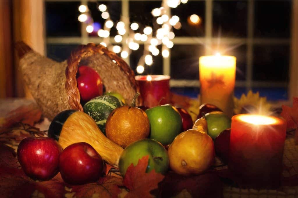 Apples and winter squashes in Thanksgiving cornucopia with candles