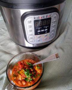 Instant Pot next to spicy lentil chili in glass mug with spoon