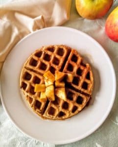 apple and peanut butter waffle on plate with syrup and apples in background