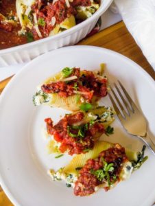 stuffed shells with kale and tomato sauce on plate