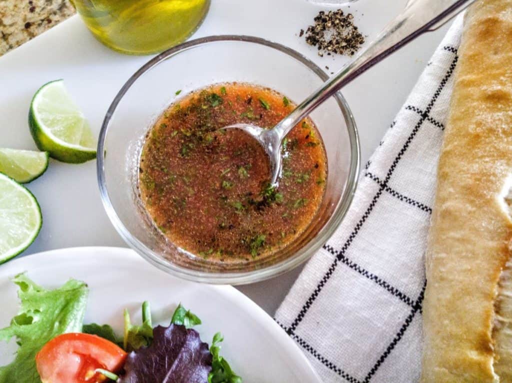tomato lime salad dressing with spoon with baguette and salad