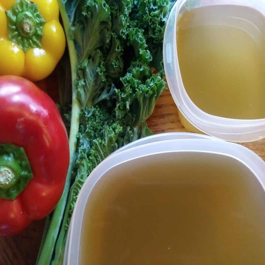 2 containers of vegetable broth with kale and bell peppers.