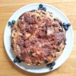 Blueberry coffee cake on plate surrounded by blueberries