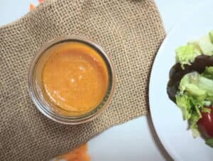 pumpkin vinaigrette salad dressing in jar on burlap with salad.